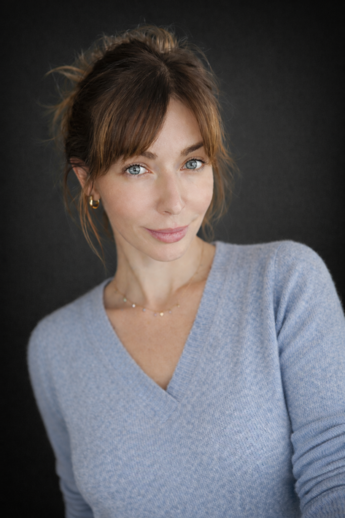 Deb is a white woman with brunette hair and blue eyes. She is wearing a blue sweater with a warm smile. 